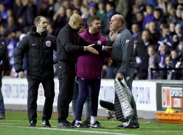 Manchester City manager Pep Guardiola (second left) and Wigan Athletic manager Paul Cook (right) exchange words