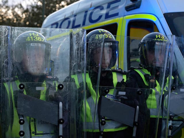 Three police officers behind riot shields and wearing riot gear in Epsom
