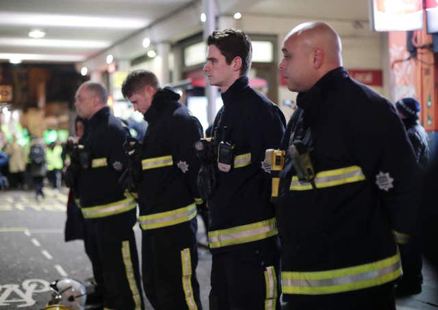 Firefighters pay their respects as people take part in a silent walk to mark the six month anniversary of the Grenfell Tower fire (Yui Mok/PA)