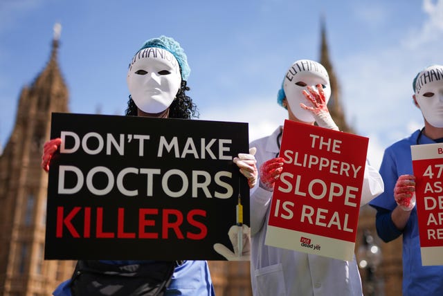 Campaigners outside Parliament wearing masks and holding placards