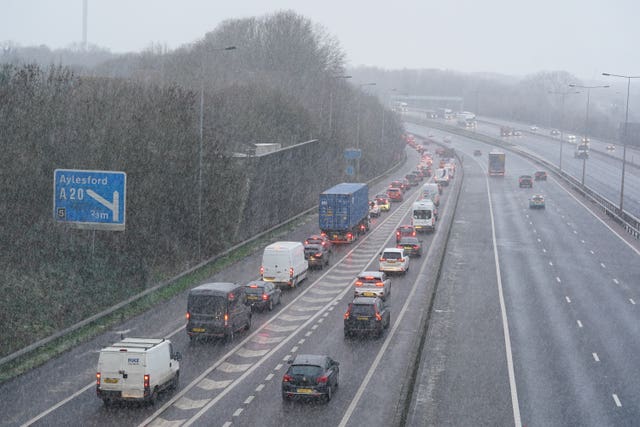 Vehicles drive through a snow shower on the M20 in Kent