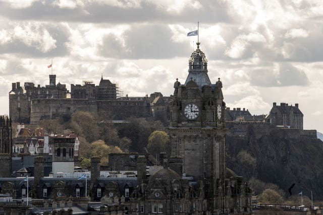 The Union flag above Edinburgh Castle (left) and the flag of Scotland on the Balmoral clock in Edinburgh flying at half mast (Lesley Martin/PA)