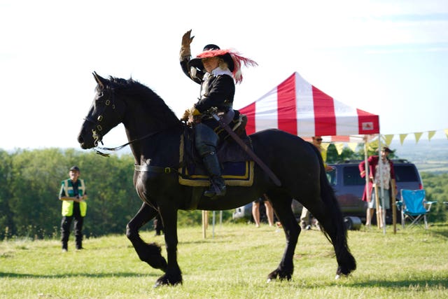 A person riding a horse in historic costume 