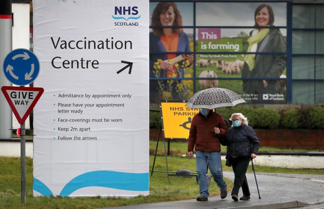 People walk passed a Vaccination Centre sign at the Royal Highland Show ground in Edinburgh 