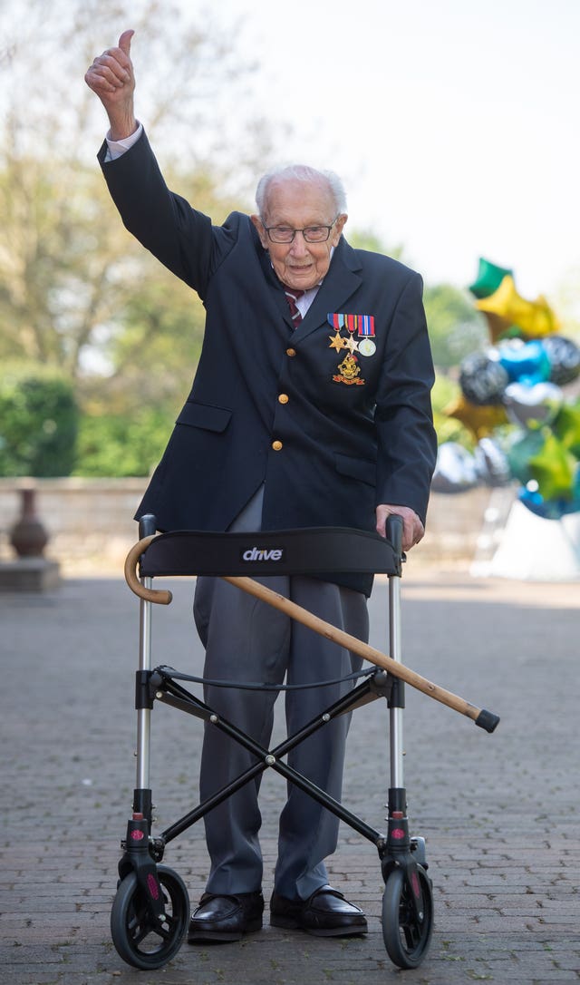 An elderly man with a walking aid raises his arm in the air