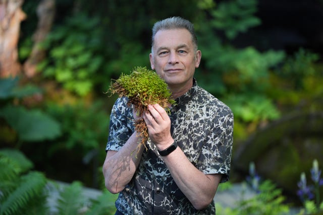 Chris Packham holds up moss on the National Autistic Society garden (Yui Mok/PA)