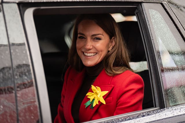 Kate, with a daffodil in her lapel, smiles through a car window as she leaves Pontypridd Market