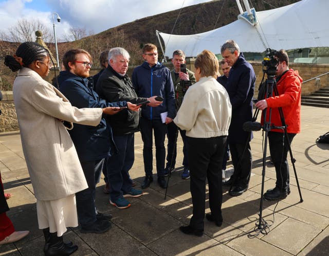 Nicola Sturgeon, with back to camera, surrounded by media