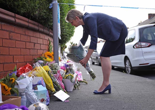 Home Secretary Yvette Cooper lays flowers against a wall