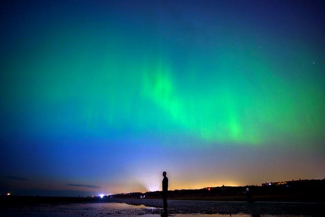 The aurora borealis, also known as the Northern Lights, glow on the horizon at Another Place by Anthony Gormley on Crosby Beach in Merseyside in May