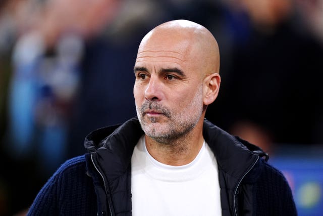 Manchester City manager Pep Guardiola wearing a dark jacket and white jumper at the Etihad Stadium