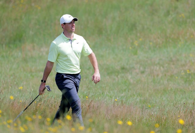 Rory McIlroy carries his club as he walks through the rough