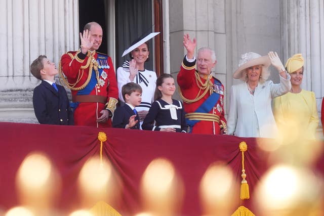 Prince George, the Prince of Wales, Prince Louis, the Princess of Wales, Princess Charlotte, the King and the Queen wave to the crowds from the balcony of Buckingham Palace as they watch the flypast