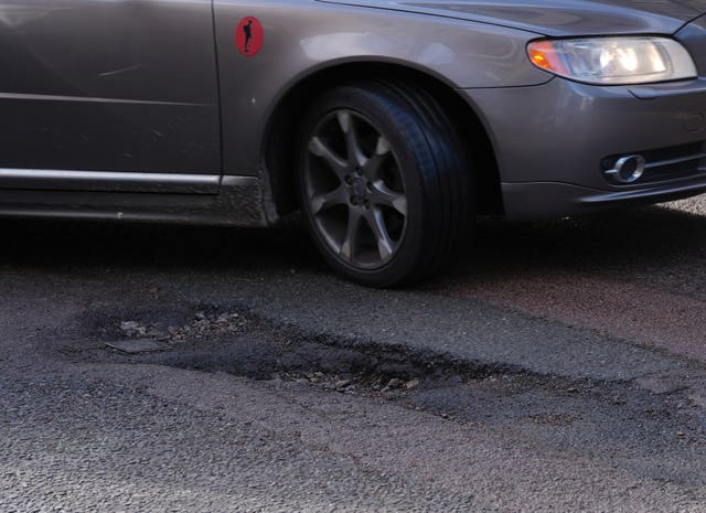 A car drives past a pothole 
