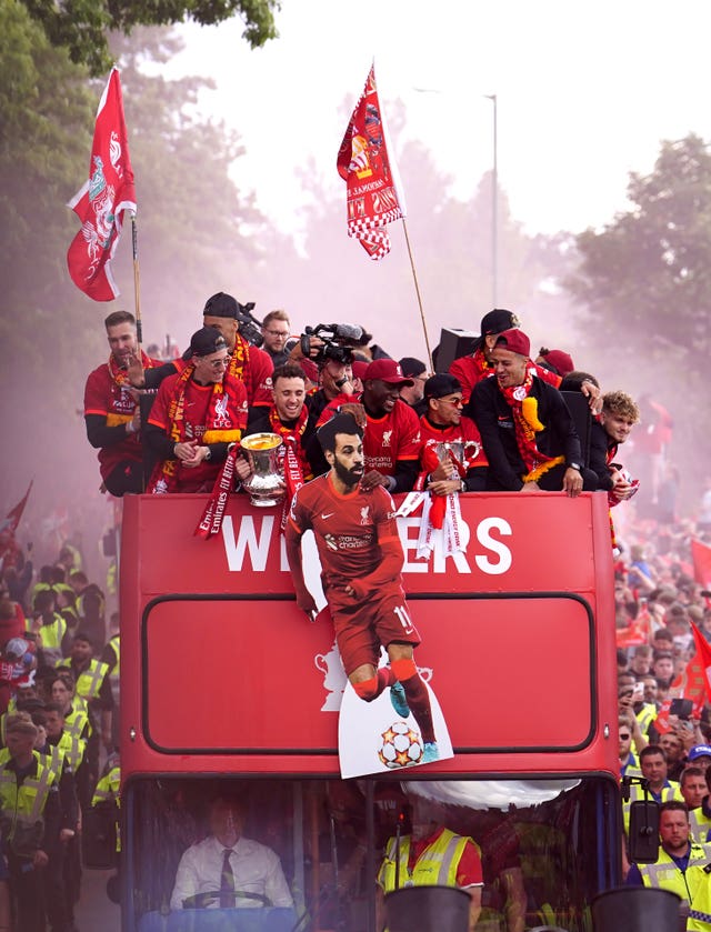 Liverpool players wave a cardboard cut-out of Mohamed Salah in front of the top deck of the bus