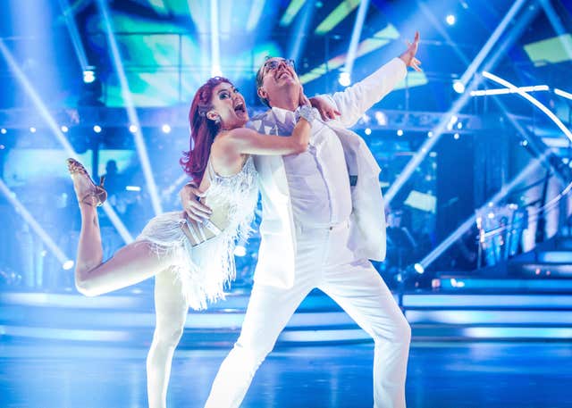 Diane Buswell with her arms wrapped around Richard Coles' neck as the pair, both dressed in white, strike a pose at the end of a dance