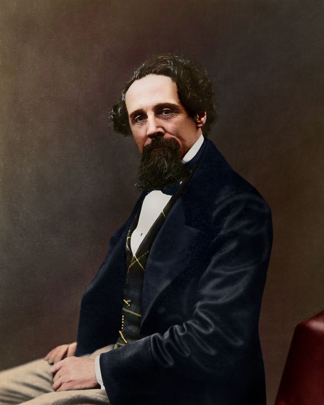 A black-and-white image to have been colourised, showing a 47-year-old Dickens with tanned skin and an ostentatious waistcoat
