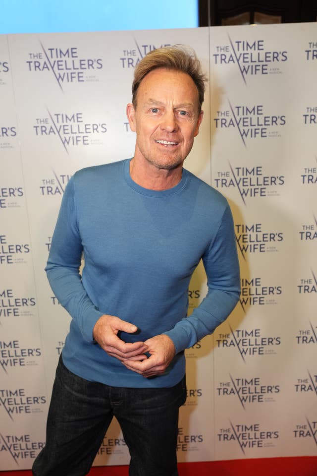 Jason Donovan wearing a blue top and dark jeans