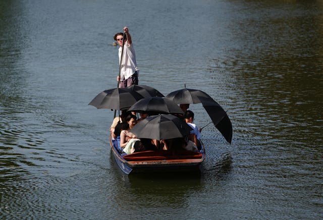 People holding umbrellas in a boat