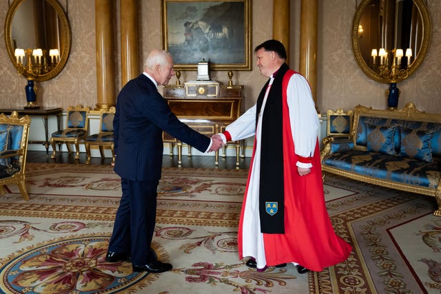 The King shakes hands with Right Reverend Graham Usher, Bishop of Norwich, at Buckingham Palace on Wednesday 