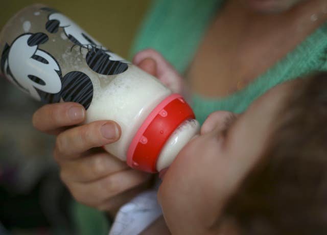 An eight month old baby boy drinking from a bottle