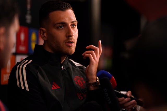Diogo Dalot raises his left hand as he talks to the media