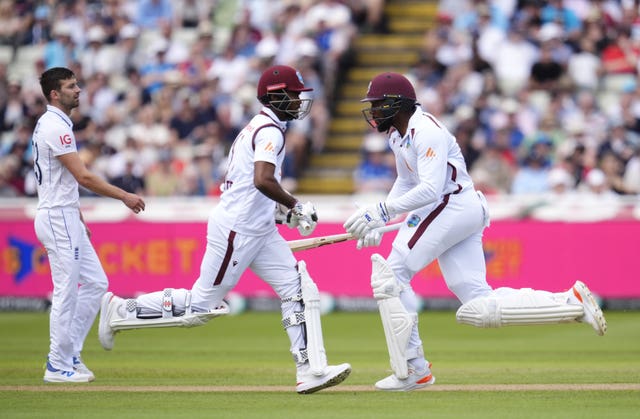 West Indies openers Kraigg Brathwaite (centre) and Mikyle Louis run between the stumps as England’s Mark Wood looks on