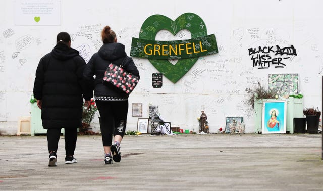 Two women walk towards the Grenfell Memorial Wall (Jonathan Brady/PA)