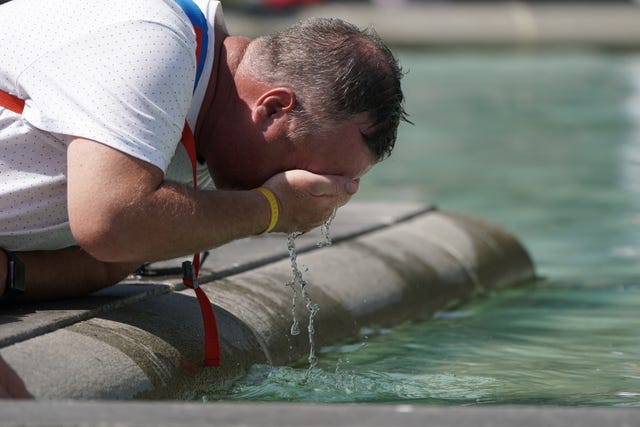 A man wets his face in the fountain