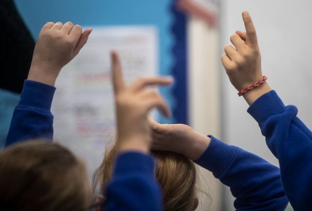 School pupils with their arms raised in class