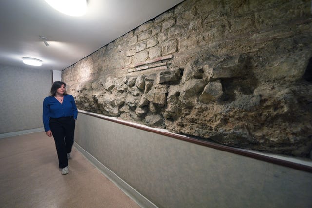 A woman walks alongside a stone brick wall