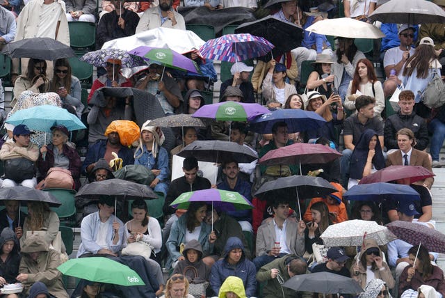 Spectators shelter from the rain on day six of Wimbledon