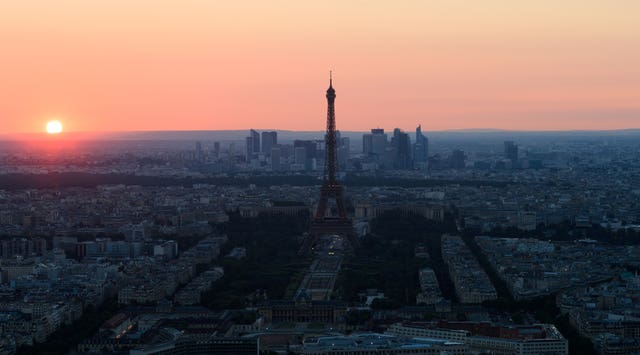 The sun sets behind the Eiffel Tower and the skyscrapers of La Defense  (John Walton/PA)