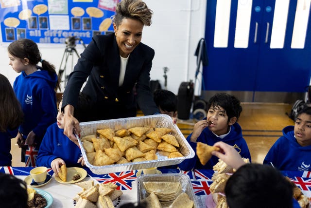 Dame Kelly Holmes shares out a tray of samosas at the launch 