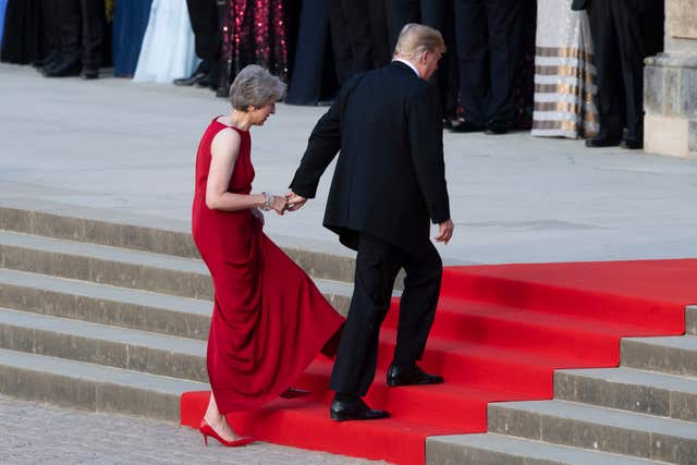 Donald Trump takes the hand of Theresa May as they enter Blenheim Palace