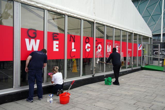 People wash graffiti off a glass wall