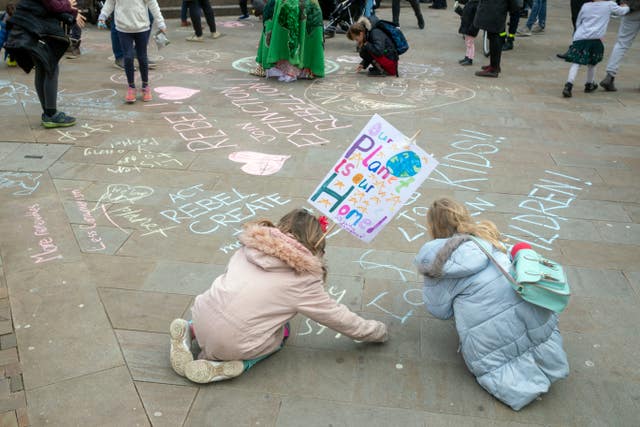 Two young girls draw on a pavement as students take part in a global school strike for climate change in Oxford city centre (Steve Parsons/PA)