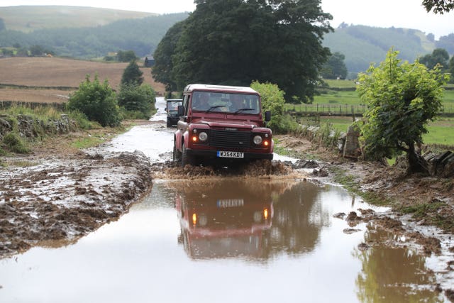 A car drives along a flooded road in Grinton, North Yorkshire