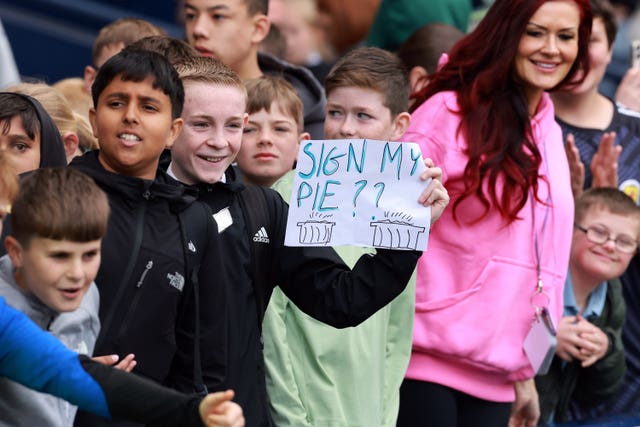 A child shows a sign reading 'sign my pie?' during Scotland's training session