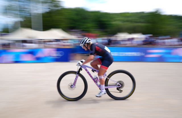 Evie Richards on her bike, with the background blurred, as she powers forward on her mountain bike. 