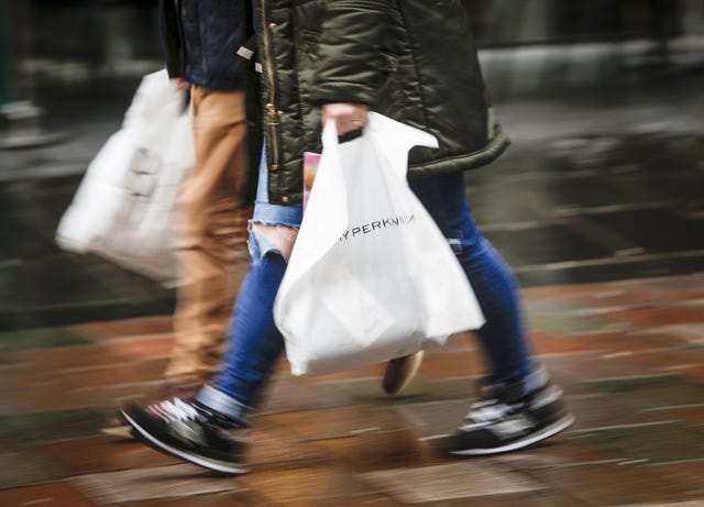 Shoppers walking down a street carrying bags