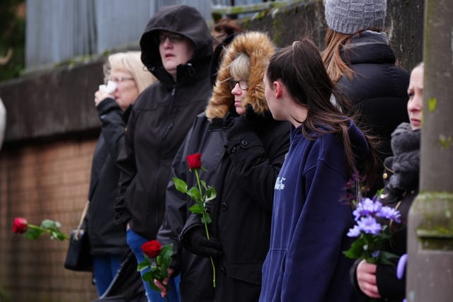 Mourners in a row with flowers