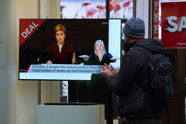 People pass a TV shop as the First Minister made a Covid-19 statement during a virtual sitting of the Scottish Parliament (PA)