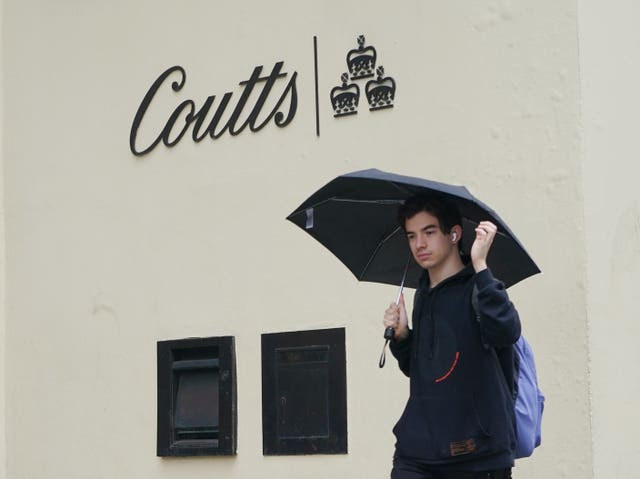 A man with an umbrella in front of the Coutts logo