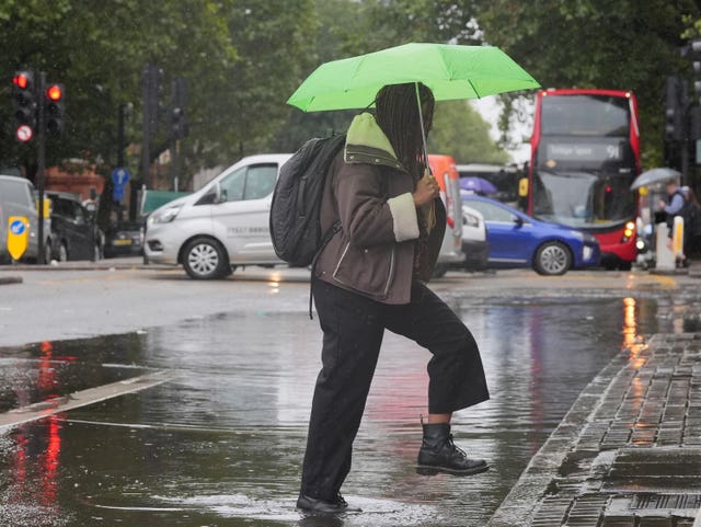 A person walks through a puddle on Euston Road in London after parts of England were lashed by heavy rain and flooding