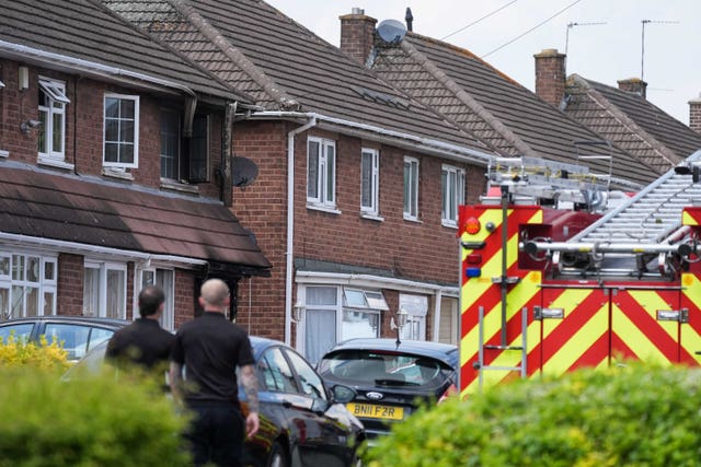 Two fire crew members standing beside a fire engine look at a burnt-out house in Wolverhampton