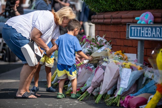 A child puts flowers on a pile of tributes near Hart Street