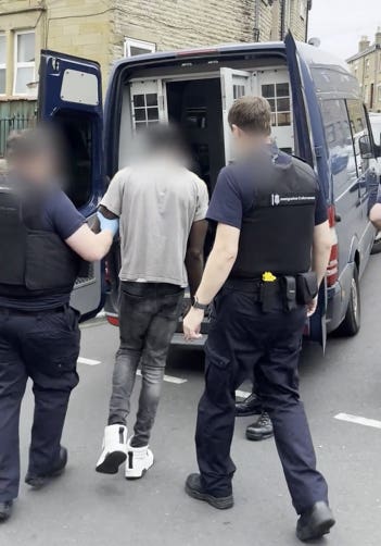 Screen grab from a video of a man being led into a police van by police officers