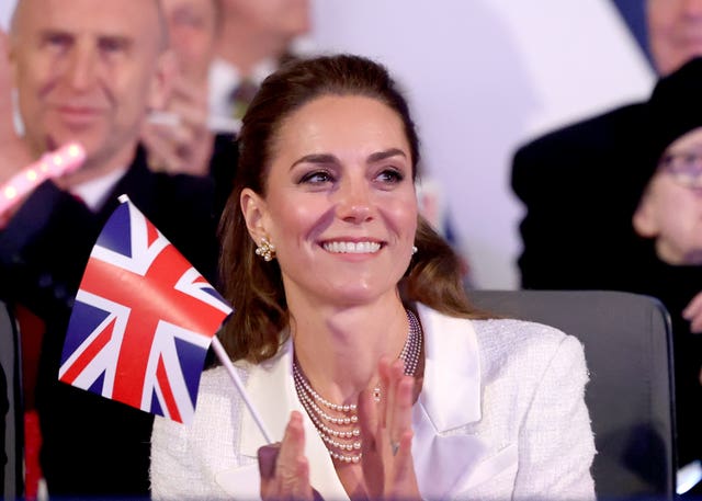 Kate smiling and applauding while holding a mini Union flag