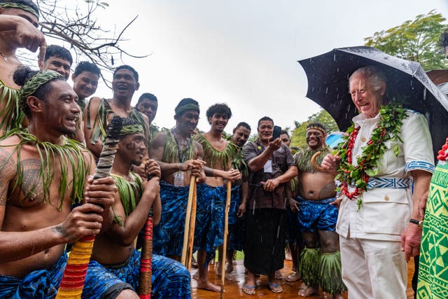 The King shares a joke with members of a cricket team during a visit to the Samoan Cultural Village in Apia 